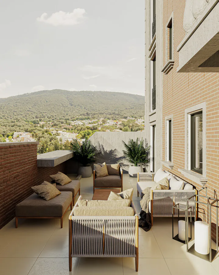 Balcón con sillones de exterior y plantas, junto a la pared de ladrillo del edificio, con vista a un cerro arbolado
