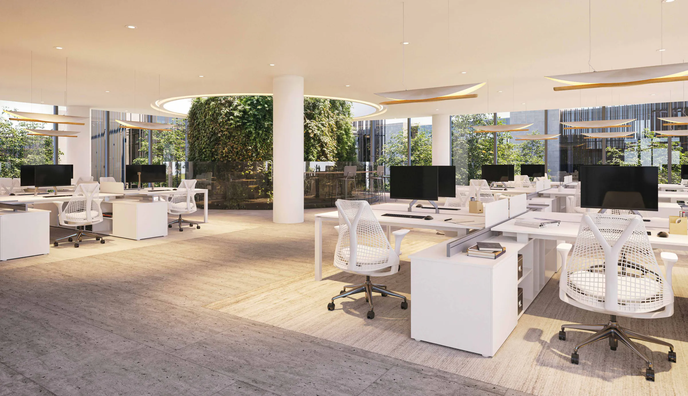 Planta libre de oficinas con escritorios blancos, sillas de malla, columnas redondas, un jardín vertical al fondo y ventanales.