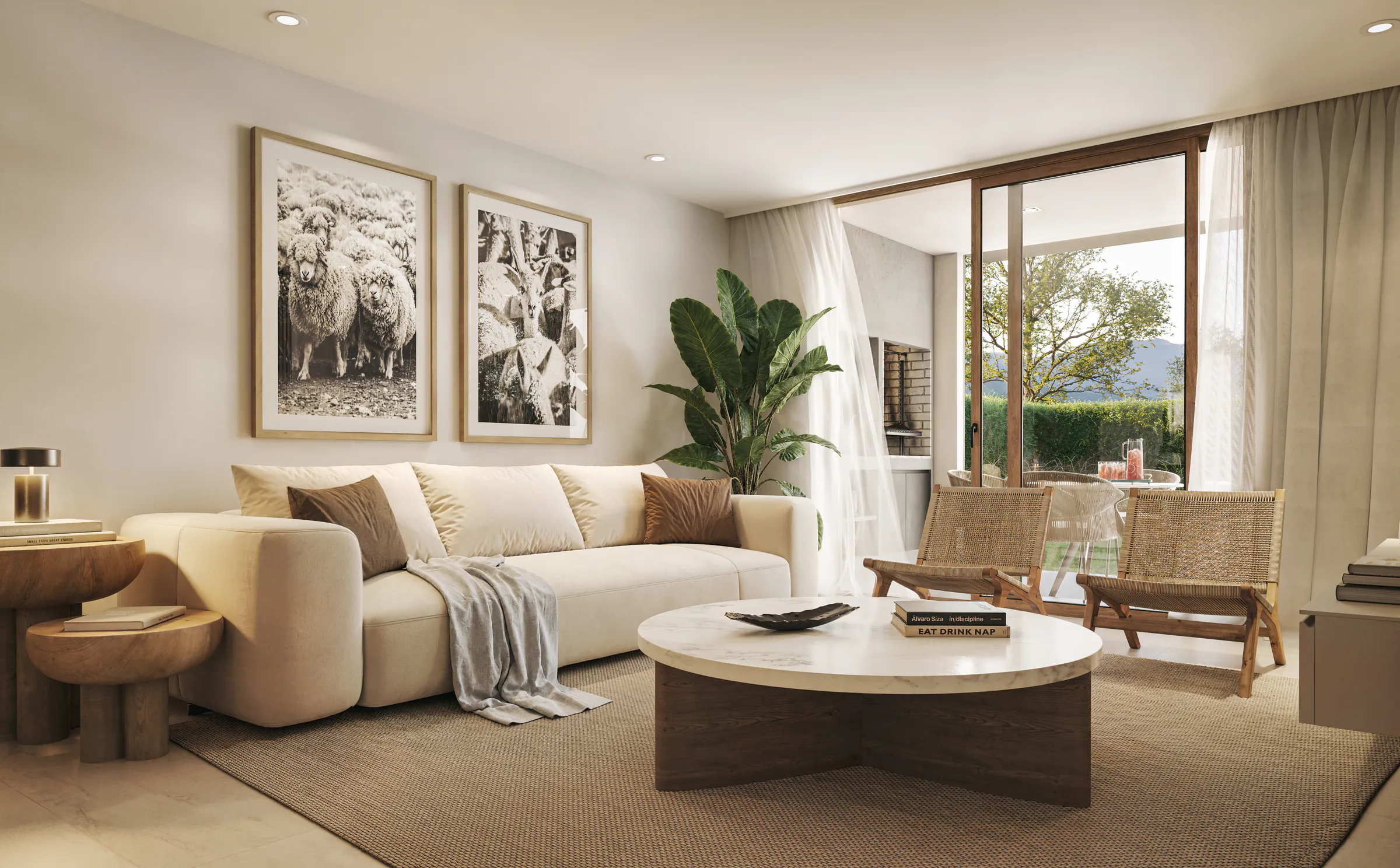 Living con sillón claro, mesa baja redonda de tapa clara sobre base de madera, dos sillones de fibra, cuadros en blanco y negro y un ventanal hacia el jardín.